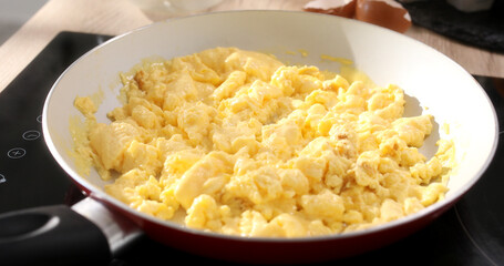 Eggs with milk are fried into a frying pan. Making an omelet. Cooking traditional breakfast from eggs. Close up. Smooth camera movement. Zoom out. Sunny day. High quality 4k footage