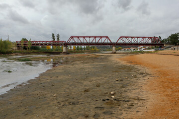 Drought in Sorraia river with Red Iron Bridge in background at Coruche, Santarem, Portugal