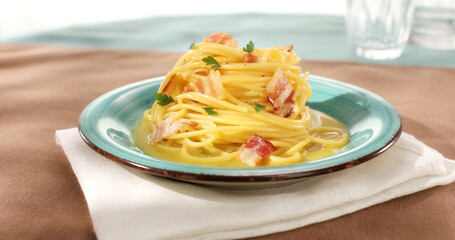 Spaghetti carbonara. Pasta with pancetta, egg, parmesan cheese. Green plate on brown background. Hard light, angle view. Traditional italian cuisine. Pasta alla carbonara.