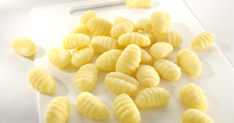 Uncooked gnocchi on cutting board. italian potato noodles on a white background. traditional mediterranean cuisine. famous italian potato dish. food on a rustic table on a sunny day.