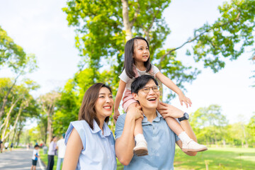 Happy Asian family spending time together travel on summer holiday vacation. Parent and little child enjoy and fun outdoor activity lifestyle walking and playing together at public park in the city. 