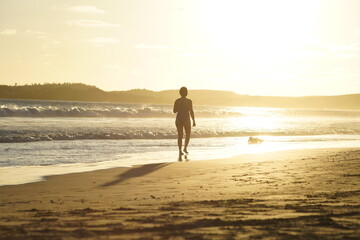 Mujer caminando sola al atardecer junto al mar