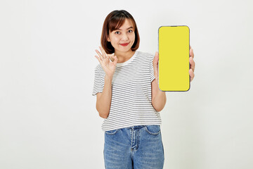 Satisfied smiling asian young woman recommending mobile phone app, website company on a smartphone, showing screen on white background.