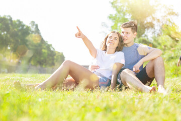 A couple of young people is sitting on the grass