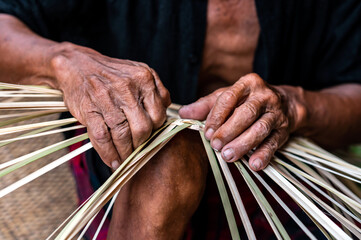 Close up Old man Hand weaving wicker basket or bamboo basketry  indoors.Weaving bamboo fish trap in Thailand.closeup view