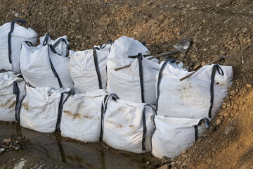 Damm aus BigBags gegen Wasser auf der Baustelle