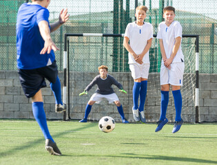 Two youth teams play football. Free kick on goal