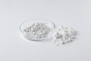 Petri dish and calcium carbonate powder on white background