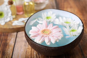 Obraz na płótnie Canvas Bowl with water and beautiful flowers on wooden table, closeup. Spa composition