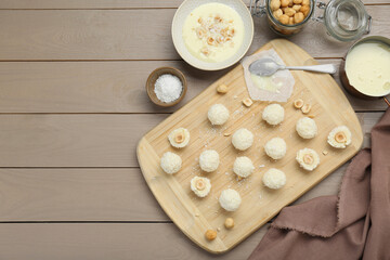 Fototapeta na wymiar Delicious candies with coconut flakes, hazelnut and ingredients on wooden table, flat lay. Space for text