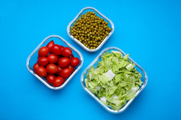 Glass containers with different fresh products on light blue background, flat lay