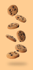 Delicious chocolate chip cookies falling on dark beige background