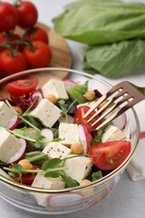 Bowl of tasty salad with tofu and vegetables on light grey table, closeup