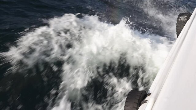 High-speed vessel sails in the open sea close-up of the port side, the movement on water is created by waves and bursts of white foam. Boat trip, speed, adrenaline impressions of outdoor activities