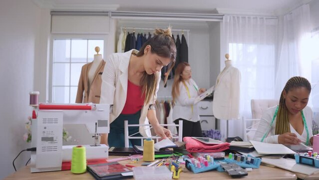 Diverse women fashion designer work design clothes in tailoring atelier.