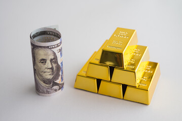 Stack gold bars and US dollar bill banknote on white background. Gold price increase rising in commodity trading bull market investment concept. Gold is store of value in recession crisis.