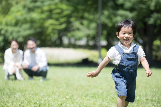 公園を走る子供と見守る親　保険や子育てのイメージに