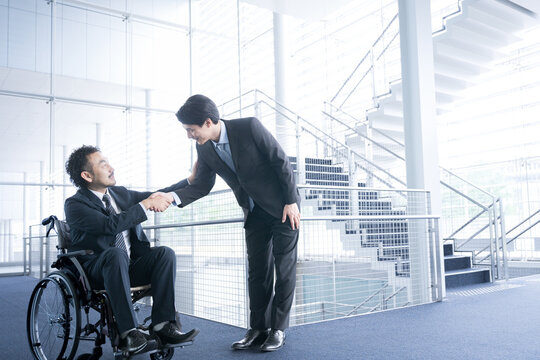 Businessperson in a suit in a wheelchair Shake hands - Powered by Adobe