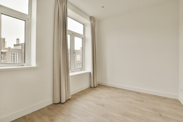 an empty room with wood flooring and large windows in the wall is white, there is a window that looks out to the