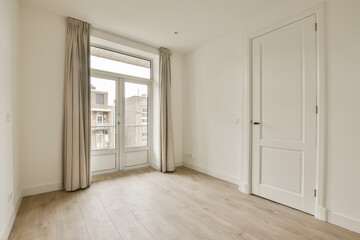 an empty room with wooden floors and white walls, there is a door leading to the right side of the room
