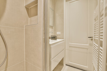a modern bathroom with beige walls and white fixtures in the shower stall door is open to reveal a large mirror