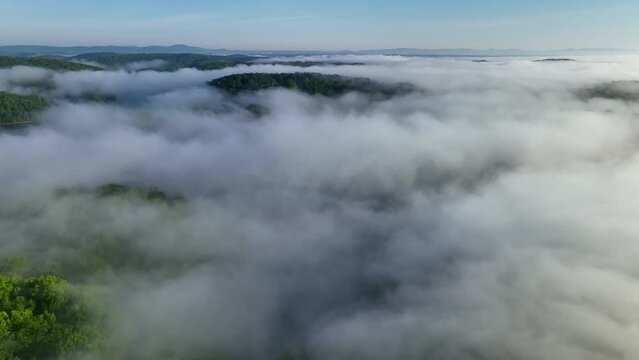Mist and fog rolls over mountains and valleys with green forest in natural environment just after sunrise in beautiful morning sunlight in Tennessee at Norris Dam and Reservoir