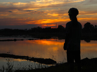 In the evening silhouettes of people standing watching the sunset with beautiful golden sky background.