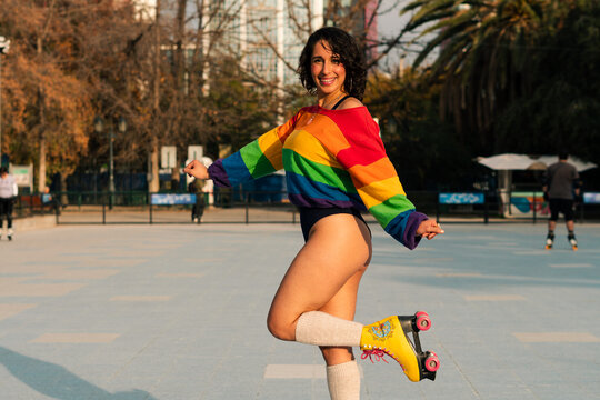 bella mujer latina sonriendo, andando en patines posando en bikini y polera de arco&iacute;ris estilo 80s 90s