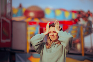 Stressed Woman Having Headaches at a Funfair Event. Fearful girl feeling dizzy and panicked at...