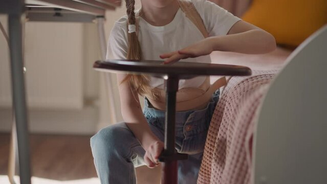 Girl with back supporting braces plays with piano stool