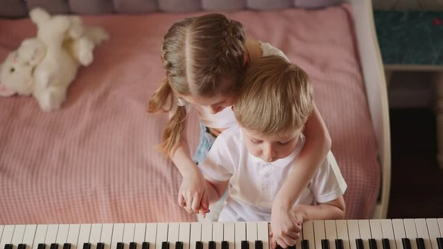Girl with braided hair plays melody on piano with brother