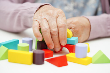 Asian elderly woman playing puzzles game to practice brain training for dementia prevention, Alzheimer disease.
