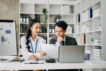 Obraz premium Two business workers talking on the smartphone and using laptop at the office.