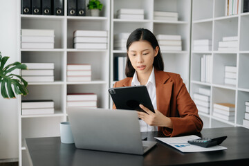 Business woman using tablet and laptop for doing math finance on an office desk, tax, report, accounting, statistics, and analytical research concept in office