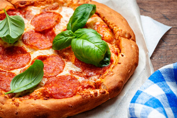 Hot pepperoni pizza with spicy salami sausage, mozzarella cheese, tomato sauce and green basil, white table background, top view