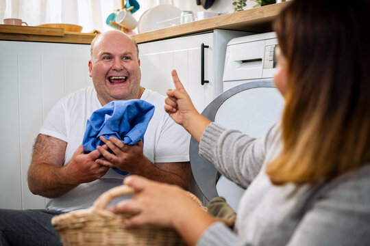 Beautiful Senior loving couple is smiling while doing laundry at home.