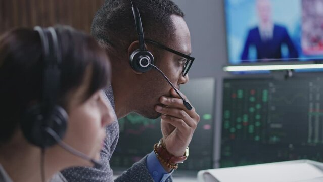 Multiracial financial analysts work on computer with real-time stocks and exchange market charts in bank office. TV news broadcast on big digital screen. Cryptocurrency trading and analytics. Close up
