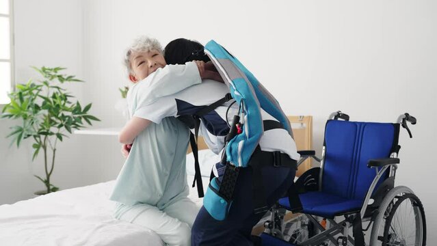 パワーアシストスーツを着けて高齢者を介助する介護士