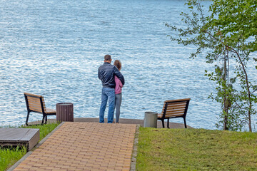 A man and a woman stand on the bank of a river on a summer day