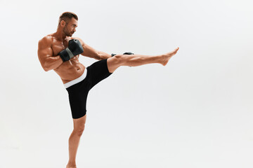 Fototapeta premium Man athletic bodybuilder poses in boxing gloves with nude torso abs in full-length background, boxing and martial arts. Advertising, sports, active lifestyle, light, competition, challenge concept. 