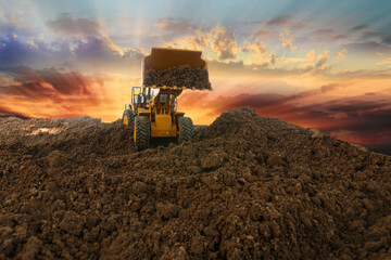 Wheel loader are digging the soil in construction site  on sunset background,with bucket lift up