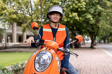 Happy young Thai motorcycle taxi driver or rider waiting for passenger near by the building in the city.