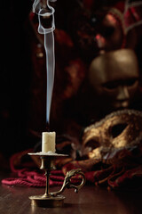 Still life with an extinguished candle and carnival masks.