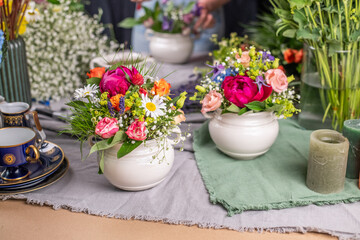 Gesteck aus frischen Blumen in einer Schale aus Keramik, Pfingstrose, Kamille, Margeriten, Clematis und Schleierkraut als Dekoration für den Tisch, Blumengesteck 