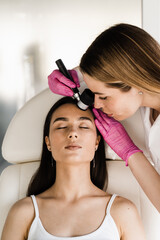 Dermatologist examines moles and birthmarks of girl patient using dermatoscope. Dermatoscopy of...