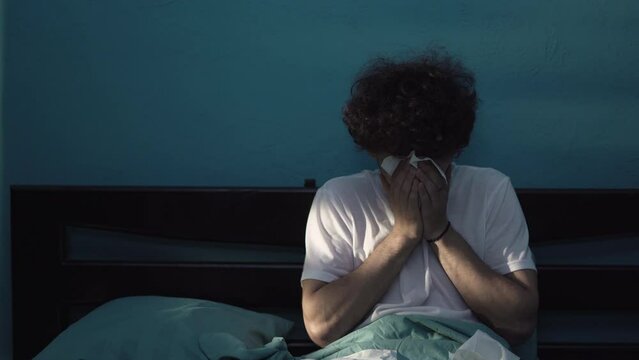 Young ill man suffering cold and flu trying to sleep in his bedroom