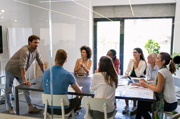 Smiling diverse colleagues gather in boardroom brainstorm discuss financial statistics together