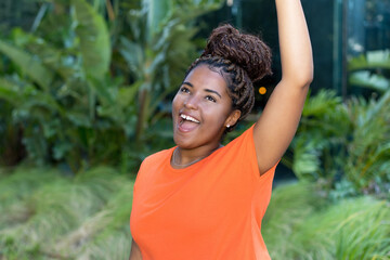 Successful cheering young adult woman from Africa with orange shirt