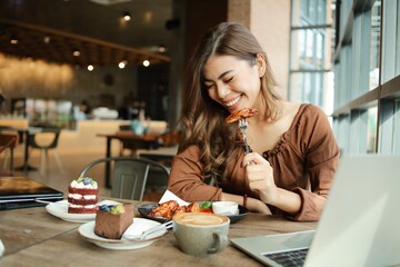 Beautiful food blogger having lunch at restaurant. Cheerful woman eating BBQ chicken wings in restaurant.