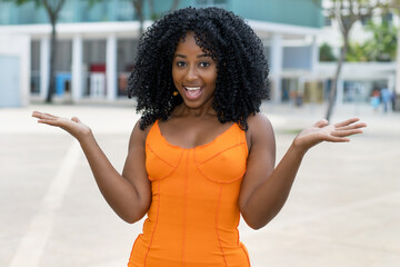 Excited brazilian woman with orange dress outdoors in summer